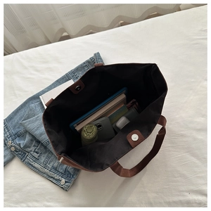 Top view of spacious brown tote bag interior holding a phone, umbrella, and tablet