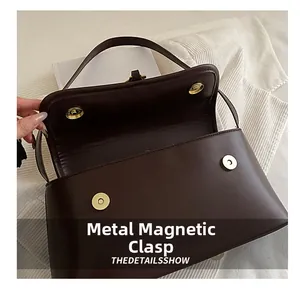 Detail view of the brown baguette bag featuring double golden magnetic snap closures