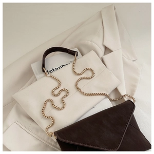 Close-up of a dark brown envelope crossbody bag with a gold chain strap and V-shaped flap