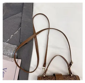 Détail de la bandoulière en cuir réglable avec boucle en métal doré sur un sac rétro