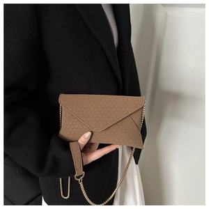 Detail of dark brown envelope clutch bag with V-shaped woven texture and gold chain strap