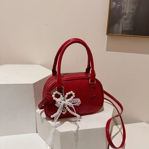Sac bandoulière rouge verni élégant avec nœud en perles et dentelle sur socle blanc