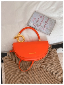 Détail du sac selle orange vif avec anneau doré et inscription Fashion & Bags