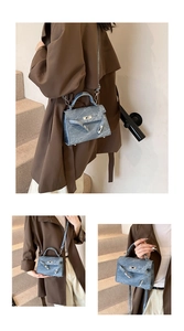 Détail du sac trapèze en denim bleu avec fermoir rotatif argenté et poignée supérieure
