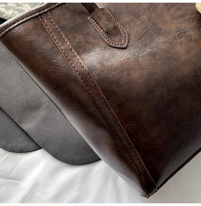 Macro detail of retro dark brown leather tote bag with vintage texture and stitching