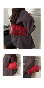 Close-up of red underarm bag featuring suede texture and gold G-shaped metal buckle