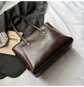 Detail of dark brown vintage tote bag with PU leather texture on white fabric