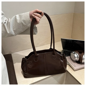 Detail of dark brown glossy leather shoulder bag with sleek stitching in a lifestyle setting