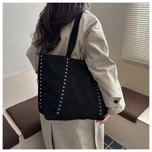 Detailed view of black suede tote bag featuring silver rivet studs and large capacity