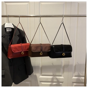 Detailed close-up of retro leather baguette bags in red, brown, and black with G-buckle