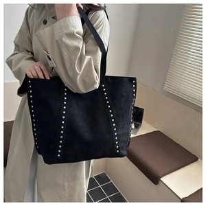 Detail of vintage black suede tote bag featuring silver studs and spacious shoulder design