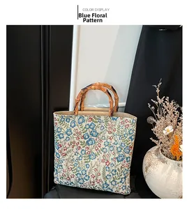 Detail of blue floral canvas tote bag with natural bamboo handles in a lifestyle setting