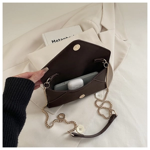 Detail of a dark brown envelope chain bag interior with phone and gold magnetic clasp