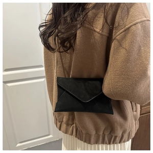 Close-up of elegant black envelope chain bag worn as a shoulder crossbody accessory