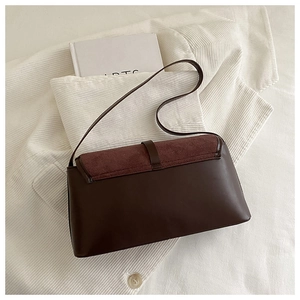 Detail of dark brown flap bag featuring mixed suede and smooth leather on white corduroy