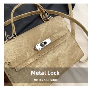 Détail du fermoir pivotant en métal argenté et du tissu sergé sur un sac style Kelly