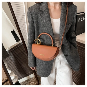 Détail d'un sac selle marron avec poignée en métal doré et logo Fashion & Bags