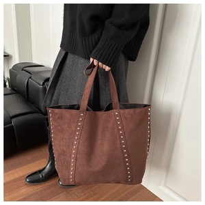 Detail of a brown suede tote bag featuring silver rivet studs and a large capacity design