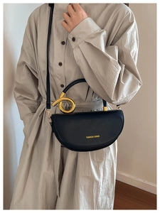 Détail du sac selle en cuir noir avec une poignée métallique dorée torsadée unique