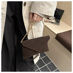 Detail of a dark brown envelope chain bag with a matte leather finish and gold beads strap