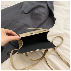 Détail du sac beige avec fermoir rotatif argenté et doublure intérieure en tissu noir