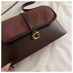 Close-up of brown suede and leather crossbody bag with vintage gold G-shaped metal buckle