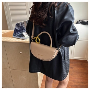 Detail of beige crescent bag with gold twisted metal rings and adjustable strap