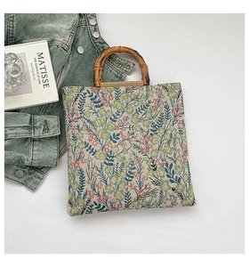 Detail of floral tapestry canvas tote with vintage bamboo handles on a white background