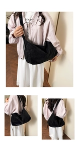 Detail view of large black crescent tote bag in matte suede with wide shoulder strap
