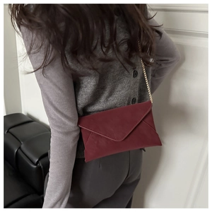 Model view showing the burgundy envelope crossbody bag with a delicate gold chain strap
