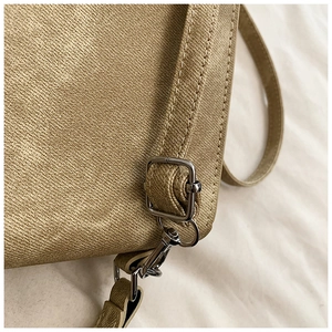 Détail du sac vintage montrant la texture du tissu gingembre et la boucle en métal argenté