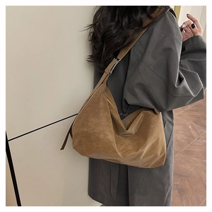 Borsa tote in pelle marrone indossata da una modella, con texture vintage e capienza