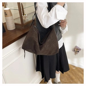 Detail of dark brown matte suede shoulder bag with adjustable metal buckle on strap