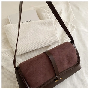 Detail of coffee and burgundy leather contrast panel on a minimalist shoulder bag