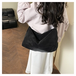 Rear view of a black large capacity tote bag shown on model in cozy home setting