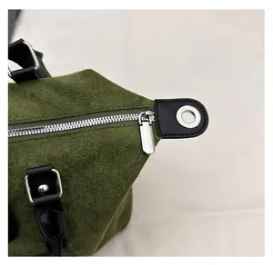 Detail of silver zipper system on dark green suede travel bag with black leather trim