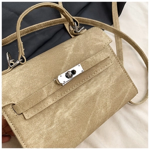 Gros plan d'un mini sac kaki avec fermoir rotatif argenté et texture grainée