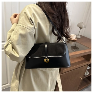 Detail of black crossbody bag featuring mixed textures and a gold G-shaped metal buckle