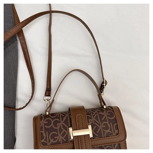 Détail du sac à bandoulière marron avec boucle en métal doré et motif monogramme