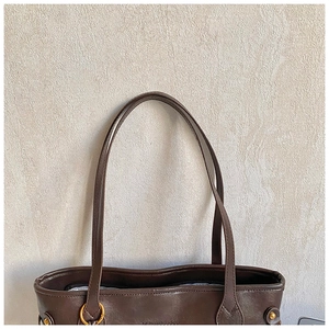 Detail of dark brown leather tote bag showing vintage texture and gold hardware