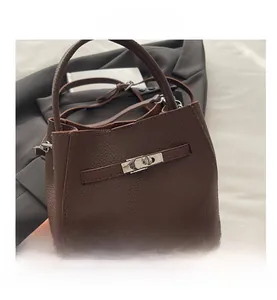 Macro detail of brown pebble leather bucket bag featuring silver turn-lock and stitching