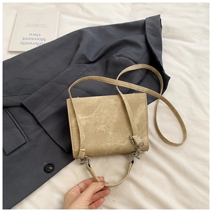 Vue détaillée du sac bandoulière en daim kaki sur lin blanc pour un look élégant et chic