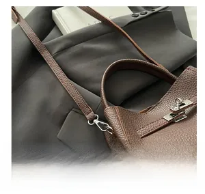 Close-up of silver metal hardware and textured lychee pattern leather on dark brown bag
