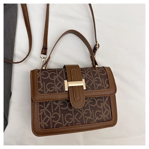 Gros plan détaillé d'un sac bandoulière vintage marron avec monogramme et boucle dorée