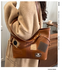 Detail of brown leather tote bag with vintage embroidery patches and slim shoulder strap