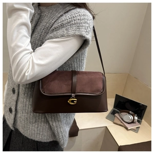 Detail of dark brown baguette bag featuring suede patchwork and gold G-shaped metal hardware