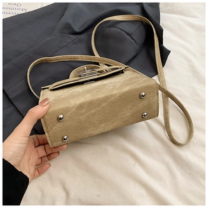 Détail du sac bandoulière kaki montrant les pieds en métal argenté et le fermoir rotatif