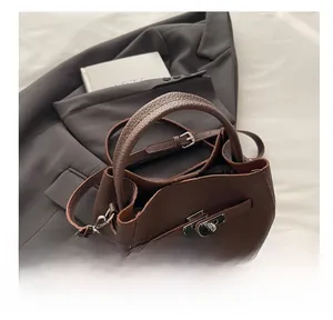 Detail of dark brown lychee leather handbag featuring classic metal twist lock closure