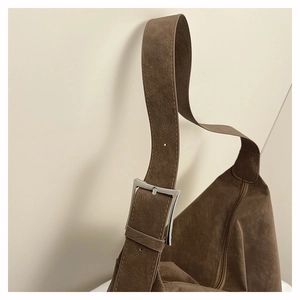 Macro shot of dark brown suede shoulder bag with adjustable silver metal buckle detail