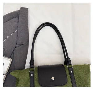 Detail view of olive green canvas handbag with black leather handle and metal fastener